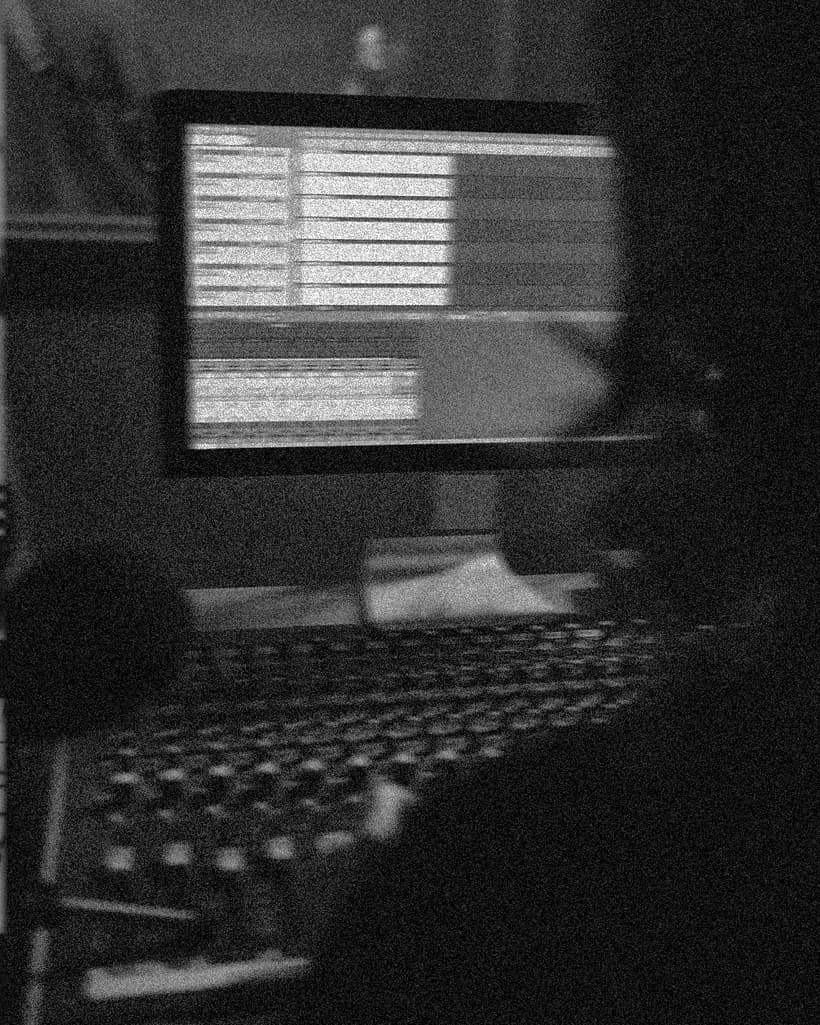 A producer working at a laptop and studio console